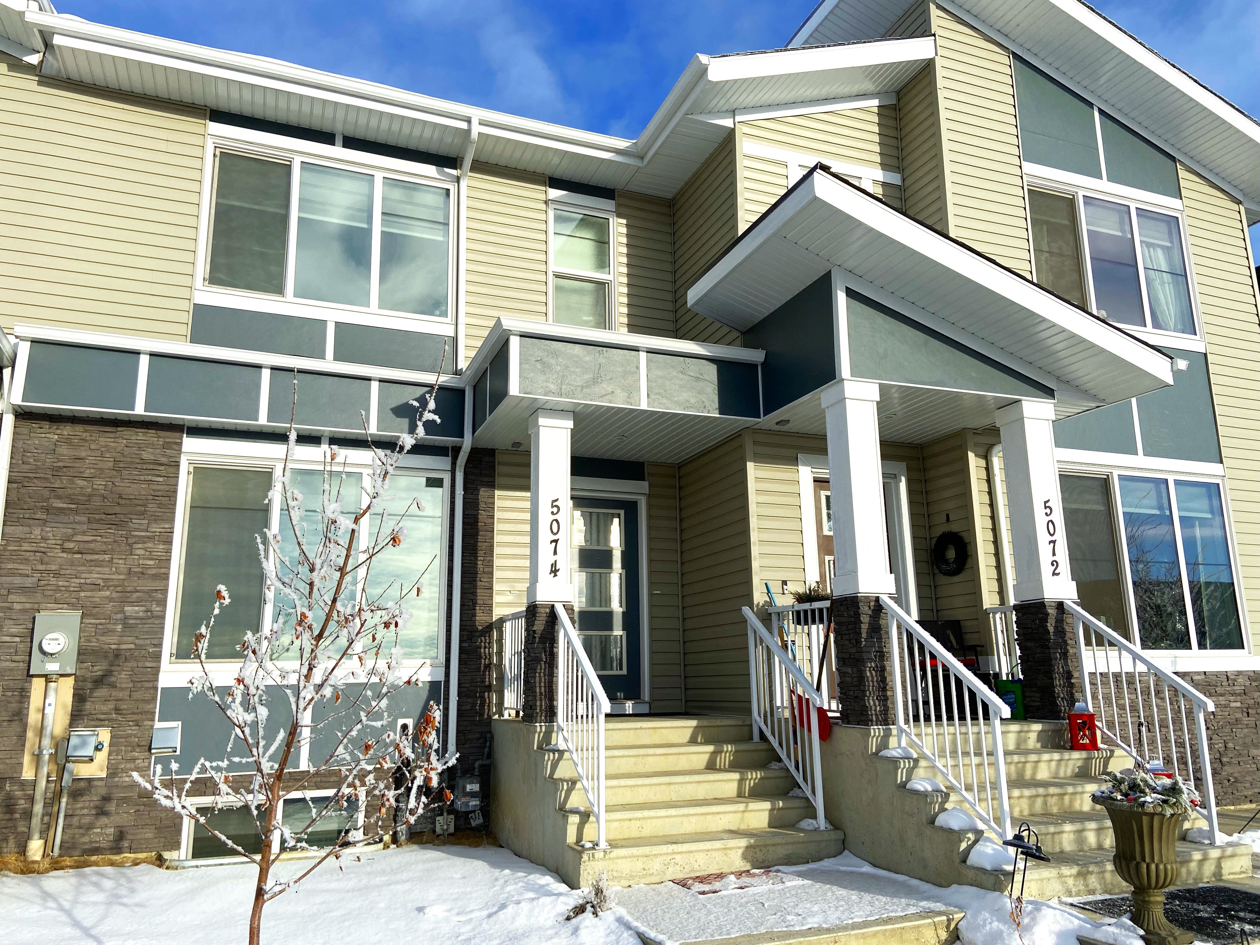 A two-story house with a front porch and a garage door.